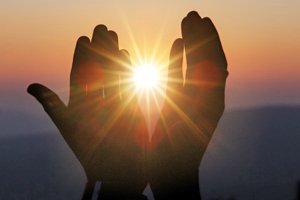 Two upright hands appearing to hold the setting sun