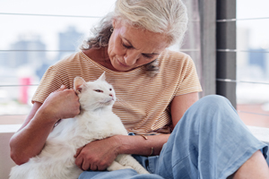 Seated woman petting white cat