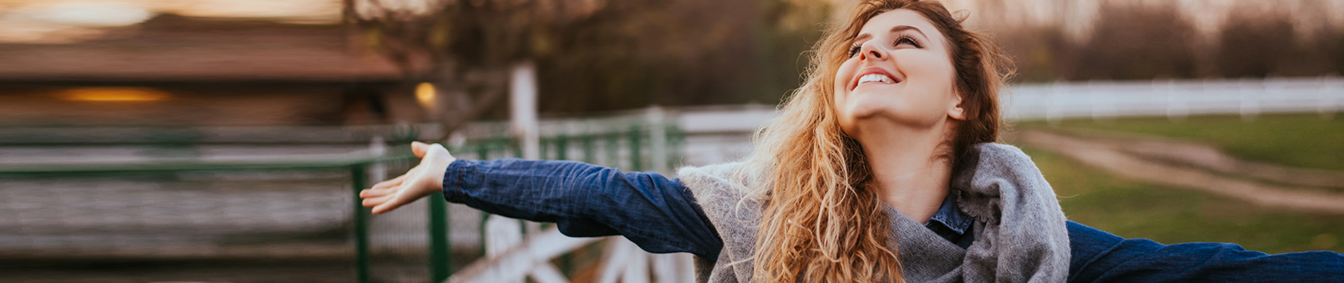 Smiling young woman with open arms looking up