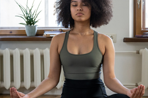 Woman sitting on floor eyes closed and meditating