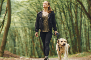 Woman walking her dog on a wooded trail
