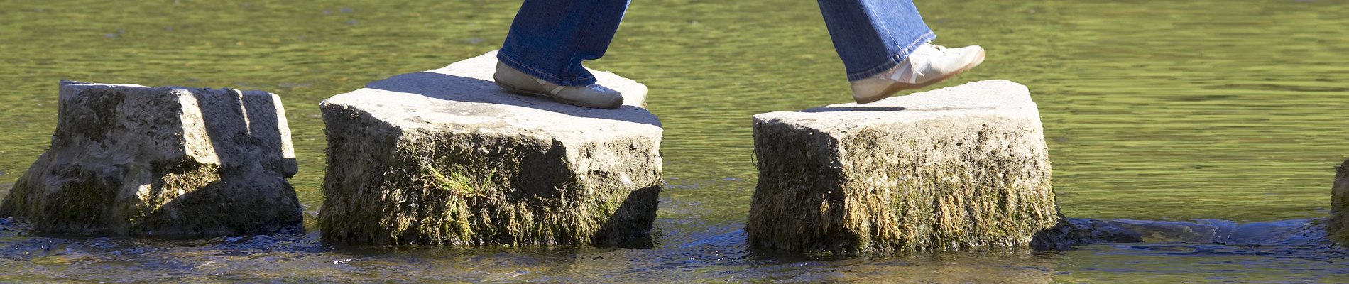 Person walking on large stones over body of water