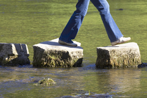 Person walking on large stones over body of water