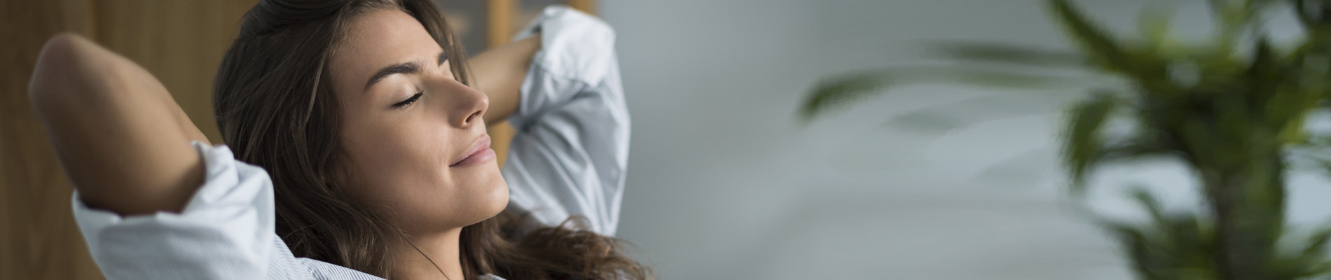 Woman leaning back with clasped hands behind head, eyes closed