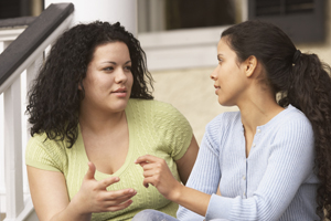 Two women have a conversation on the steps