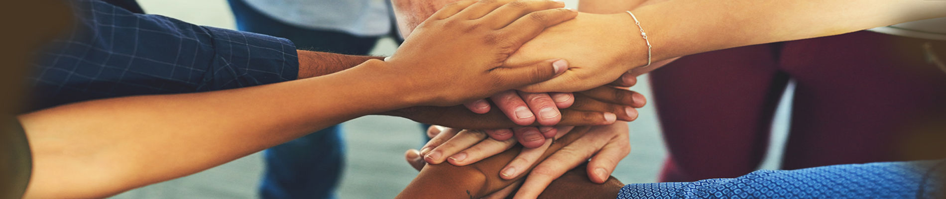 Seven hands joined/stacked in a circle indicating unity and commitment