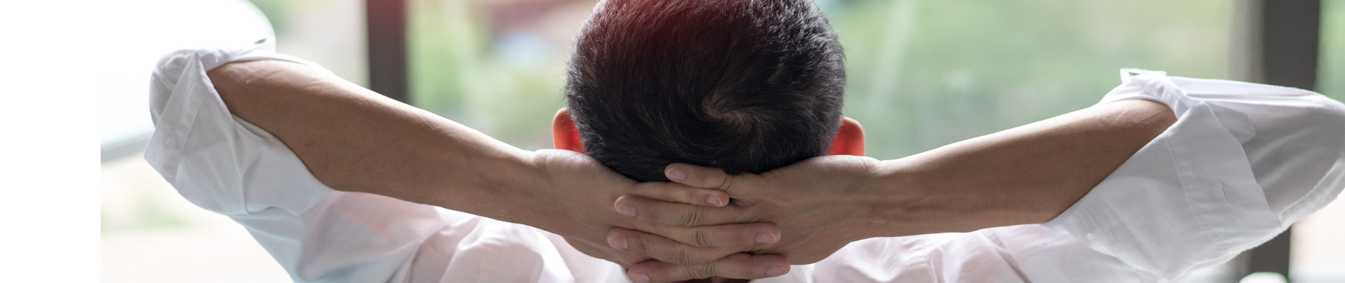 man leaning back in chair with hands folder behind his head