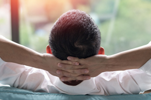 man leaning back in chair with hands folder behind his head