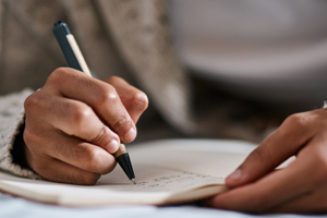 Woman¿s hands holding and writing in a journal