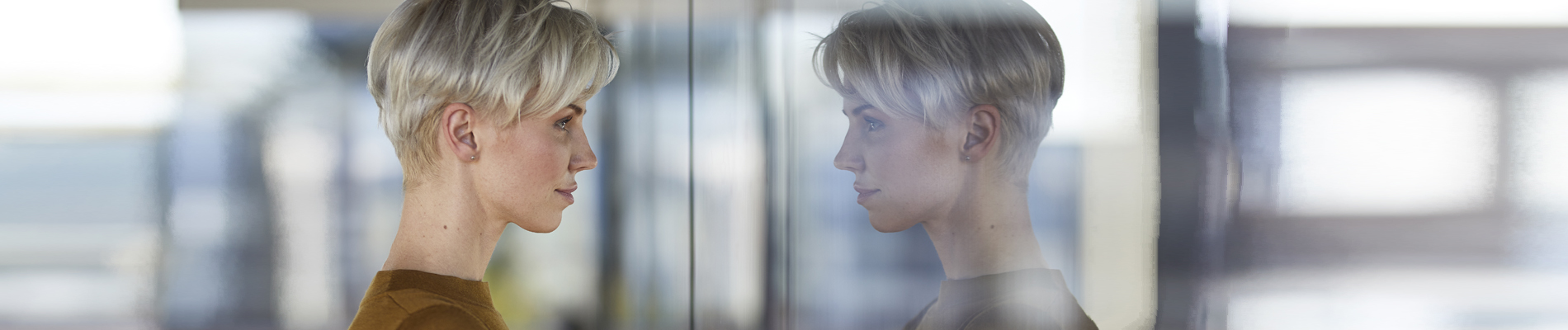 Woman looking at her own reflection in a window pane