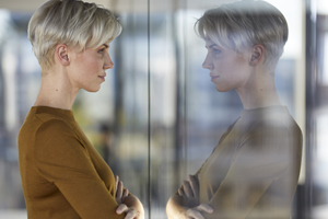 Woman looking at her own reflection in a window pane