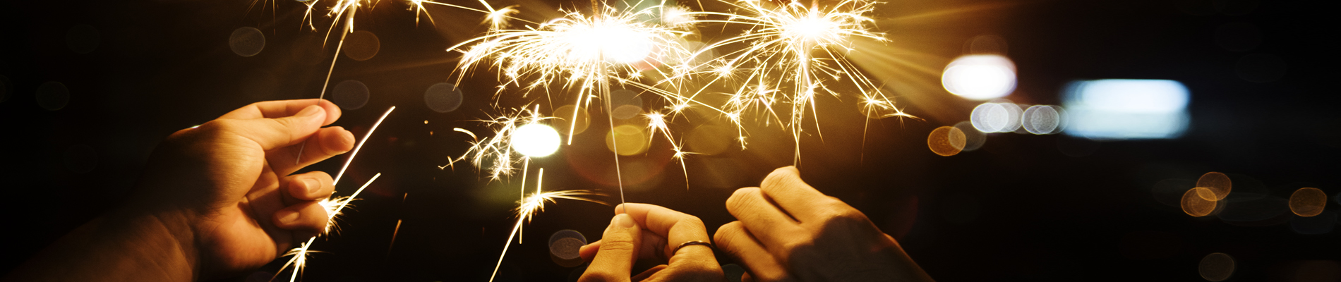 three hands holding lit sparklers