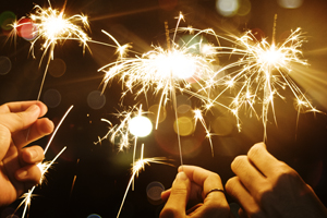 three hands holding lit sparklers