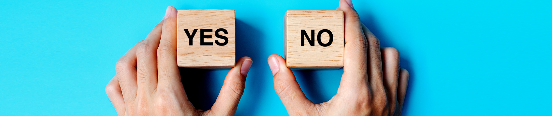 Hands holding two wood blocks, one yes and one no block