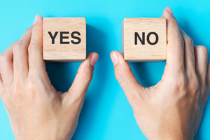 Hands holding two wood blocks, one yes and one no block