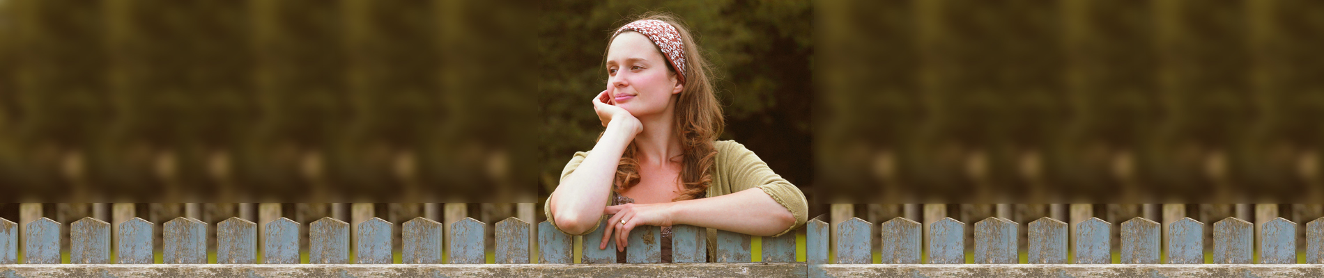 woman leaning on a picketed fence in thought