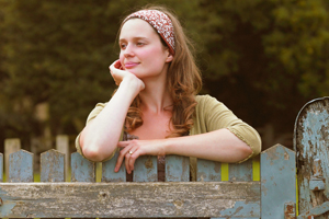 woman leaning on a picketed fence in thought