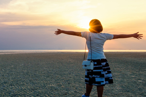 woman with outstretched arms at low tide looking towards sky