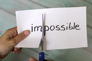 Paper being cut dividing the word impossible to possible