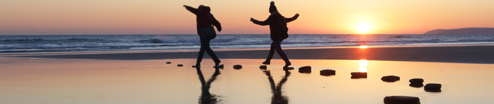 Two people walking on stone path at low tide in pool of water
