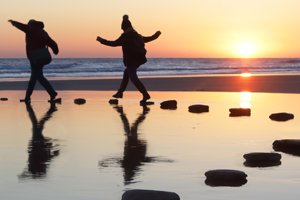 Two people walking on stone path at low tide in pool of water