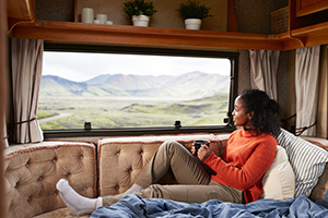 Woman sitting on a couch looking out an RV window over a valley