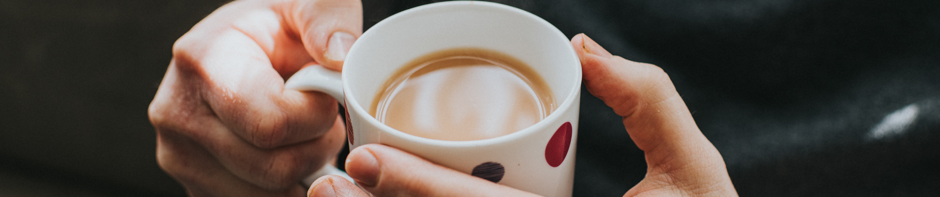 Hands holding a full cup of coffee