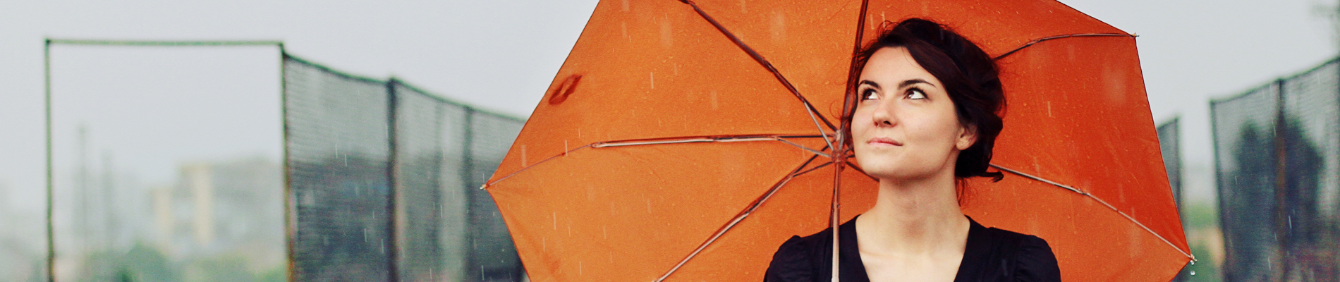 Woman walking on a metro street holding an open umbrella on shoulder