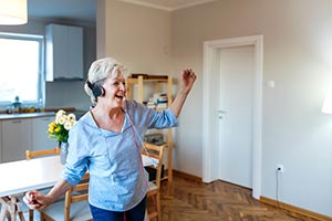 A woman in a kitchen with headphones singing and dancing