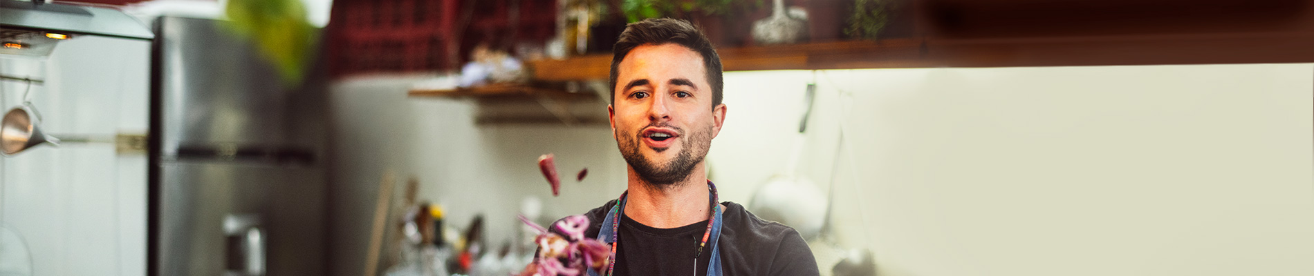 A man in a professional kitchen talking about making and tossing a salad