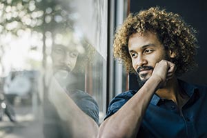 Man gazing out window seeing his reflection