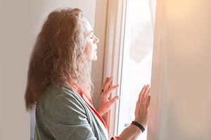 Woman reflecting at a window filled with sunlight