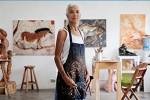 A woman standing in a room with paintings on the wall