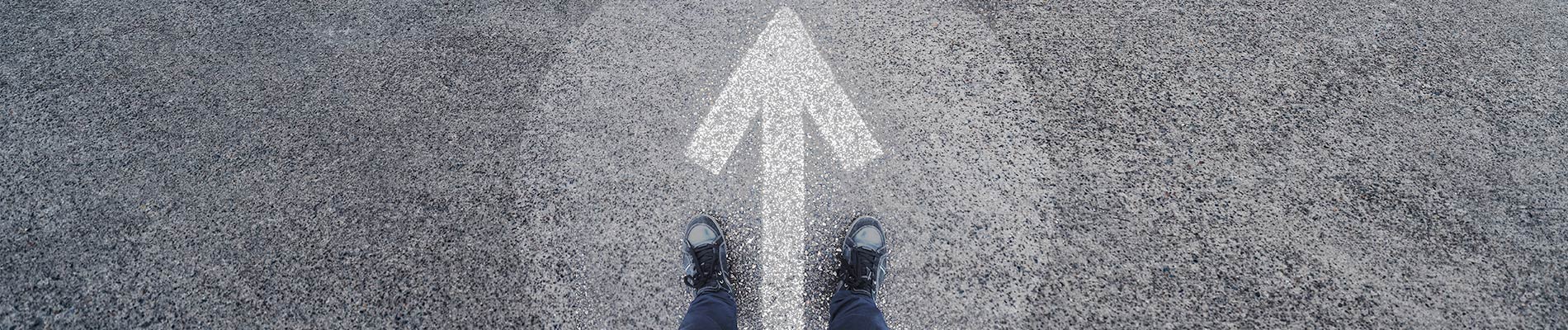 A pair of feet standing within a circle with a white directional arrow pained within it