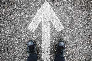 A pair of feet standing within a circle with a white directional arrow pained within it
