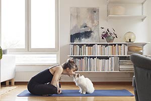 A woman sitting on the floor touching noses with a white cat