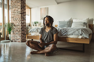 Man sitting on the floor legs crossed meditating