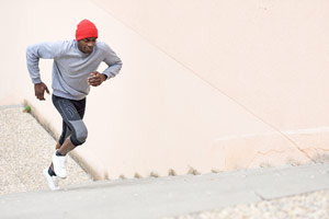 Man in a red stocking cap running a long a sandy shoreline