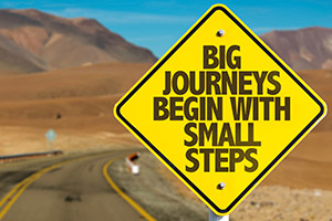 Empty six lane highway with a sign stating Big Journeys Begin With Small Steps