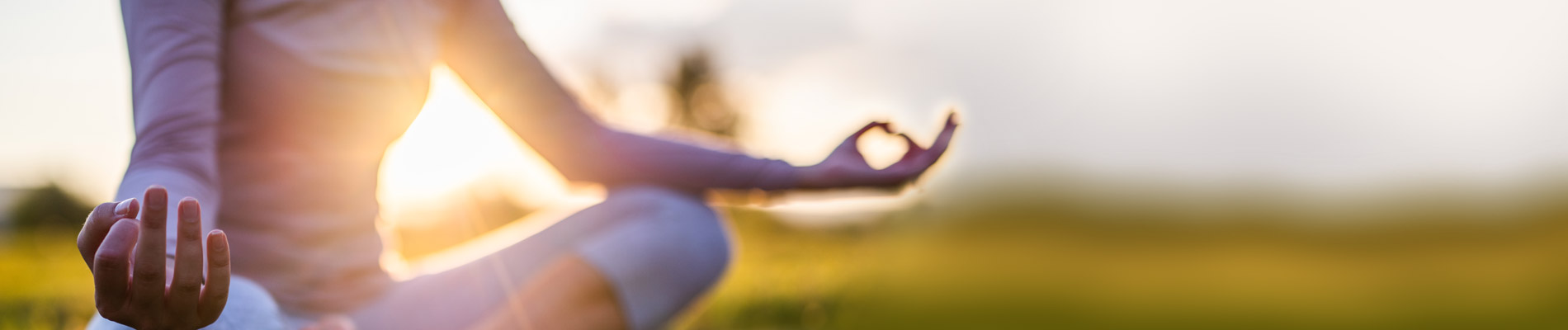 Woman sitting in a grassy area in a yoga position