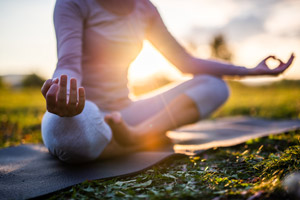 Woman sitting in a grassy area in a yoga position