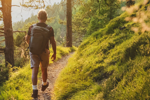 A man with a backpack walking on a trail through the woods