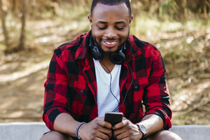 a man sitting on a park bench next to his bike texting