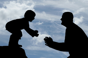 dark silhouette of a child about to leave to fathers arms with a bright blue sky background