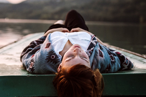 Woman lying on a platform by a lake