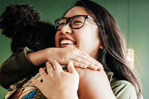 two women in a warm embrace smiling