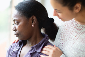 distressed woman being consoled by another woman on a porch