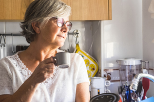 woman holding a coffee cup at the kitchen sink looking out the window