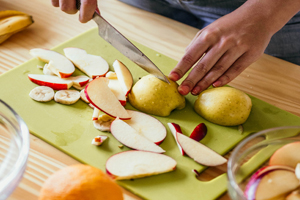fresh apples, bananas, cherries and pears being cut up