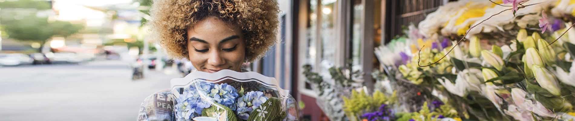 a young woman holding a bouquet of fresh cut flowers on a sidewalk